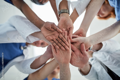 Doctor  hands together and below with medical team for meeting  unity or motivation at hospital. Low angle or closeup of group piling or touching in collaboration  solidarity or mission at clinic