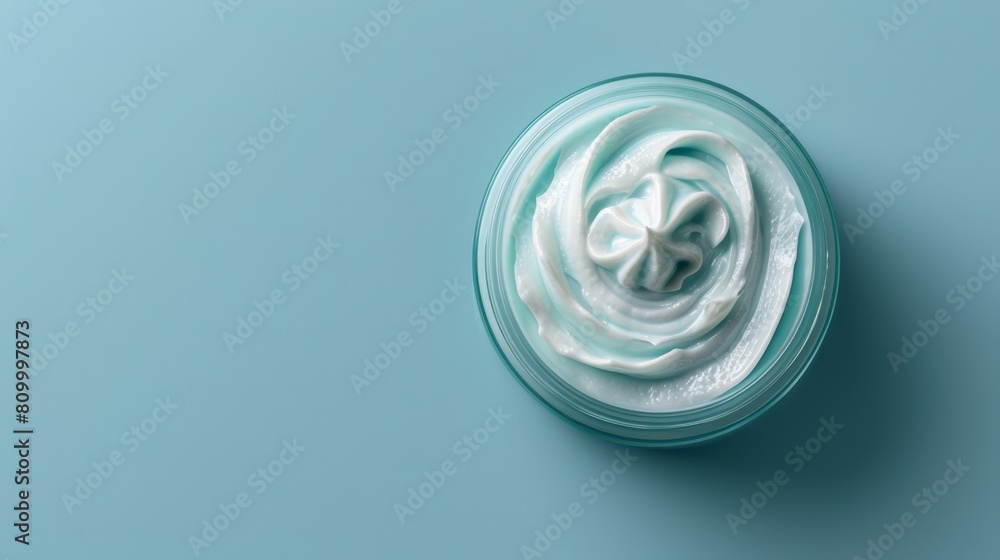 A jar of whipped cream atop a blue counter, sporting a white swirl as its center A jar of whipped cream atop a blue counter, sporting a white swirl as its center