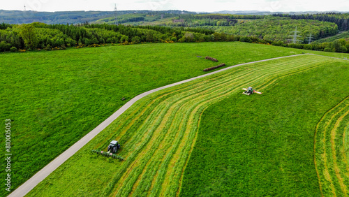 Obraz na płótnie Landwirte mähen eine Wiese und wenden das Gras (Luftaufnahme)
