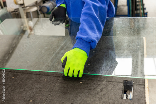 A glazier places sheets of glass on a professional table. Work in a glass factory, specialized professions and work in industry