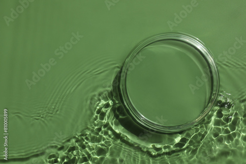 Stylish presentation for product. Glass podium in water on pale green background  top view. Space for text