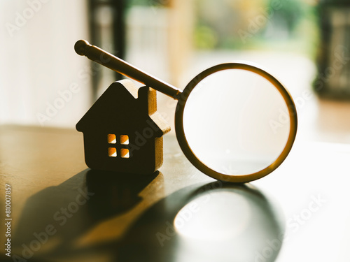Magnifying glass and looking at house model, house selection, real estate concept. photo