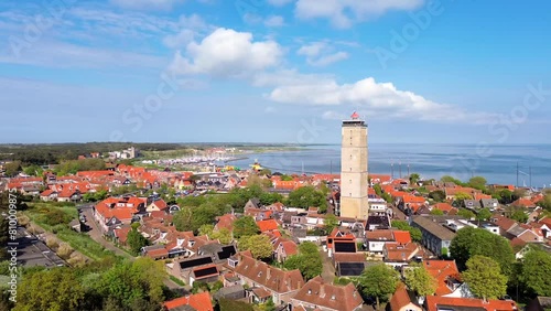 Aerial drone film of the town of west Terschelling with iconic landmark, brick lighthouse brandaris with historic town under blue summer skies photo