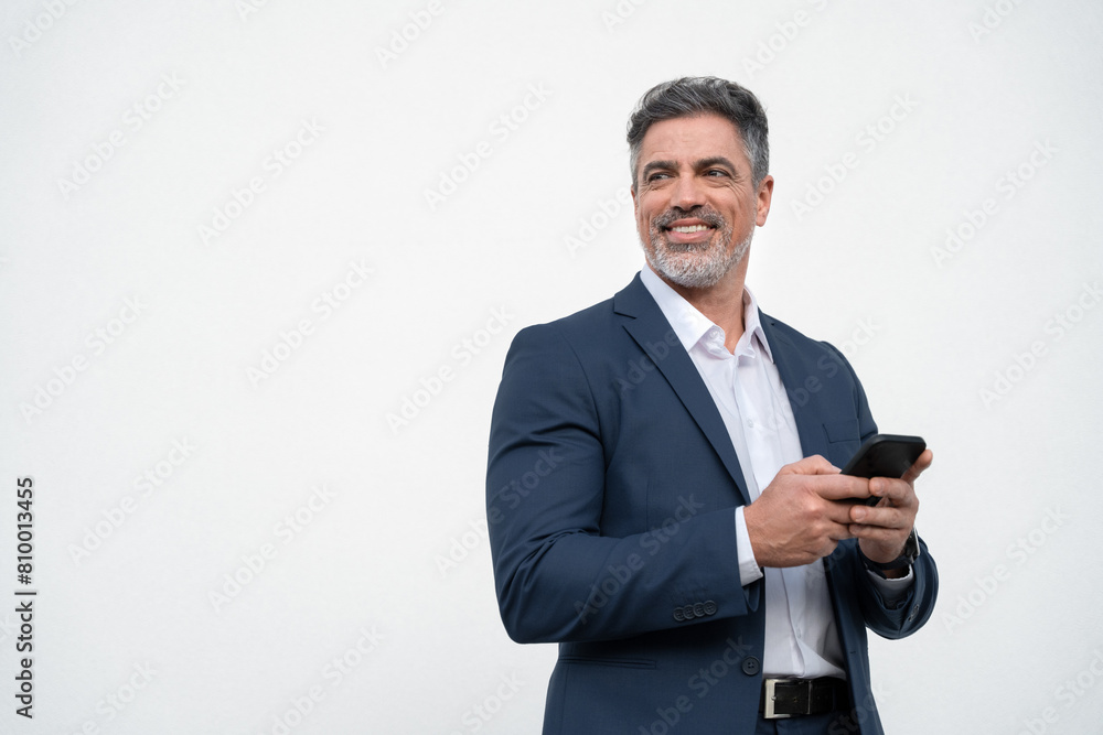 Mature businessman in suit holding cellphone isolated, white background. Smiling Latin business man using smartphone mobile phone screen device, scrolling app, working and looking aside. Copy space Mature businessman in suit holding cellphone isolated, white background. Smiling Latin business man using smartphone mobile phone screen device, scrolling app, working and looking aside. Copy space