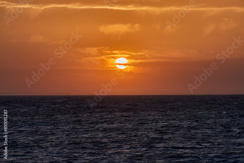 Cloudy orange sunset on dark ocean