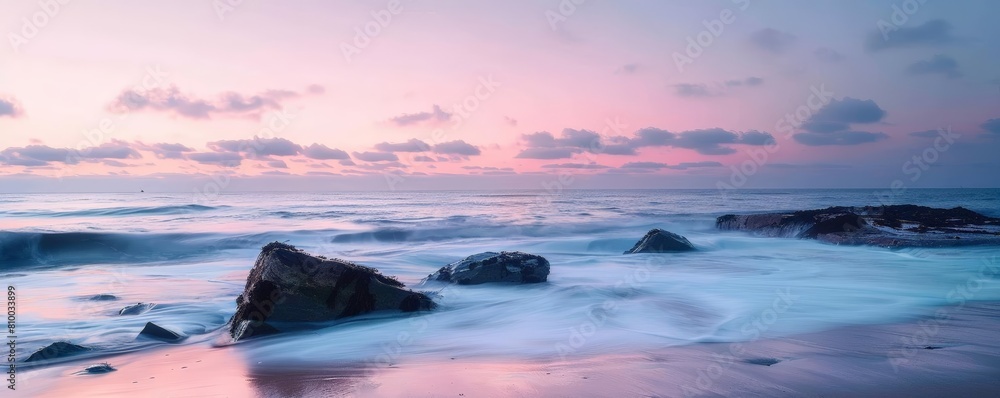 minimalist coastal landscape with soft sunset hues featuring large rocks and a dark cloud against a blue sky