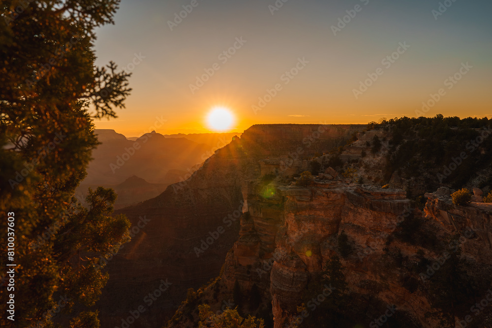 Scenic sunset at Grand Canyon with red rock layers glowing in golden light, vast horizon, and serene atmosphere. Ideal for nature and landscape enthusiasts.