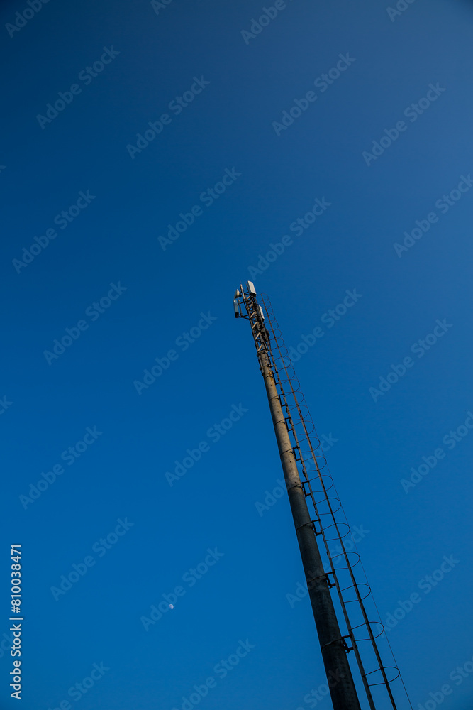 a tall pole with a ladder on it against a blue sky a tall pole with a ladder on it against a blue sky