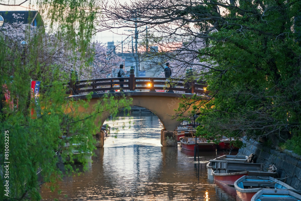 People on bridge to Mihashira Shrine in Yanagawa river at sunset