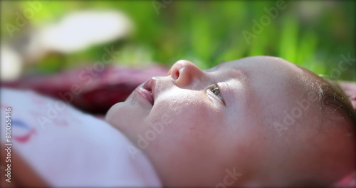 Newborn baby infant lying on grass outdoors in dreamy day