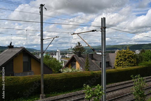 Roofs of houses along a greenway with electric poles in the middle of a green area in the Swiss village of Urdorf. photo