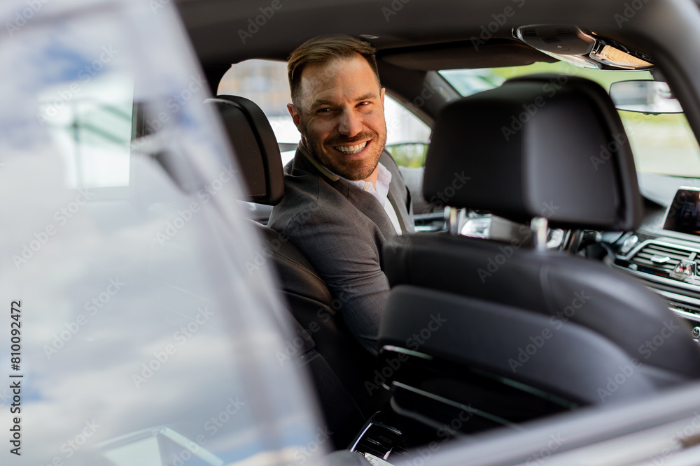Welcoming smile from a joyful driver in a luxury sedan on a sunny day Welcoming smile from a joyful driver in a luxury sedan on a sunny day