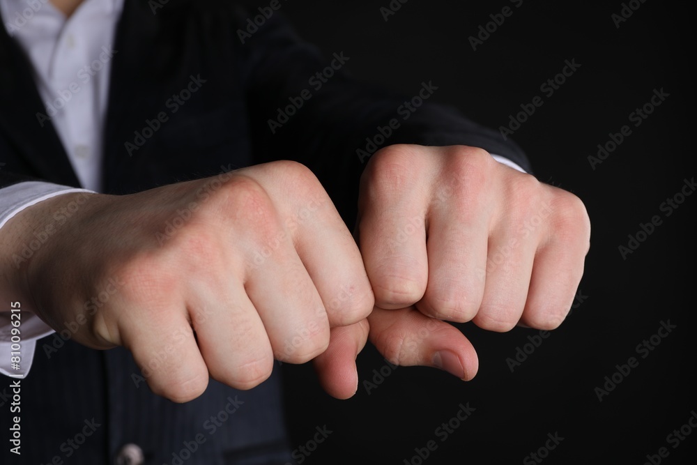 Businessman showing fists with space for tattoo on black background, closeup Businessman showing fists with space for tattoo on black background, closeup