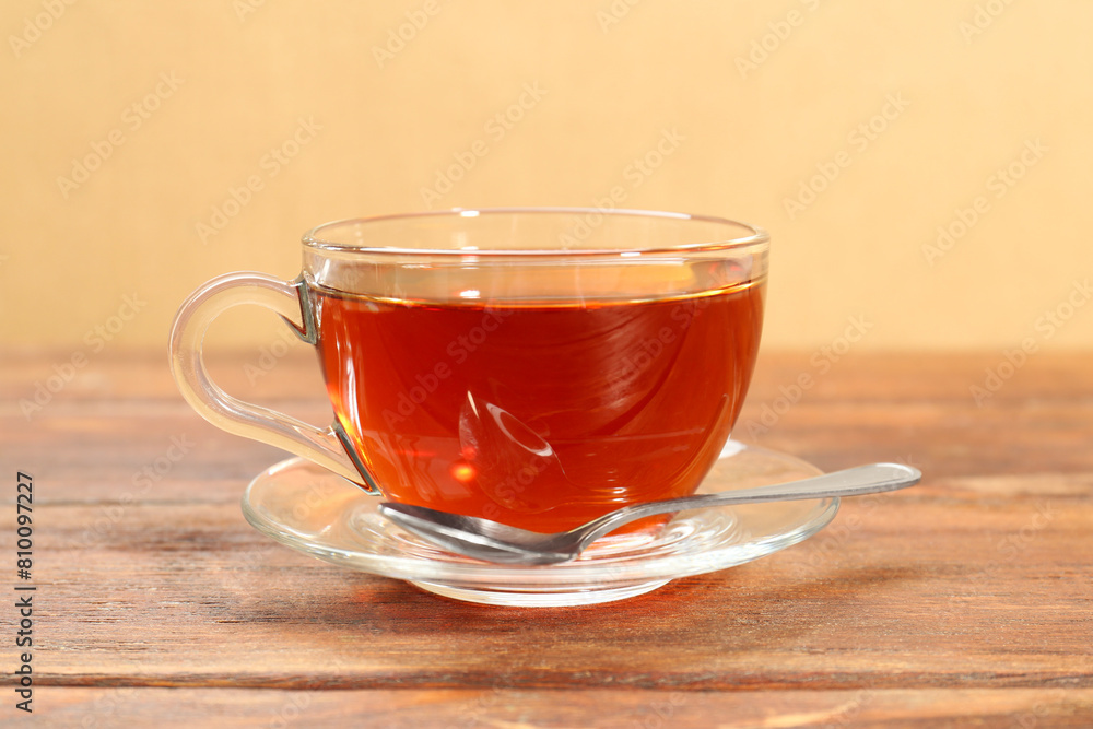 Glass cup of tea and spoon on wooden table Glass cup of tea and spoon on wooden table