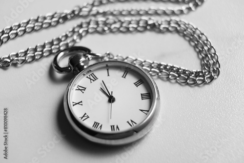 Silver pocket clock with chain on light table, closeup