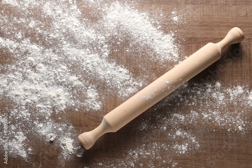 Scattered flour and rolling pin on wooden table, top view