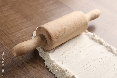 Flour and rolling pin on wooden table, closeup