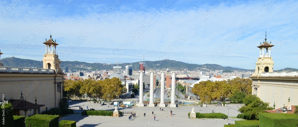 Obraz premium View from the National Palace of Barcelona, ​​panorama of the city and view of the mountains - historical sights of Catalonia - a magical fountain, a palace and urban buildings