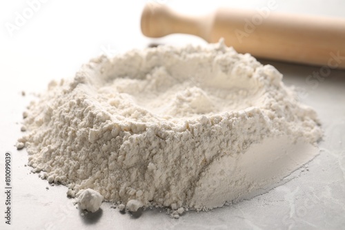 Pile of flour and rolling pin on grey marble table, closeup