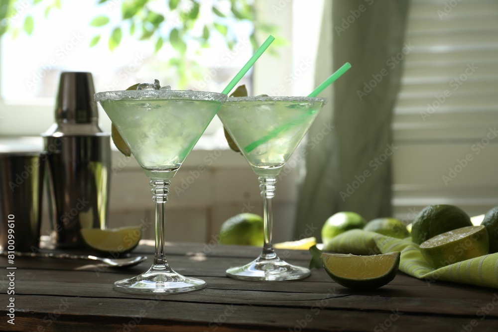 Delicious Margarita cocktail in glasses and lime on wooden table Delicious Margarita cocktail in glasses and lime on wooden table