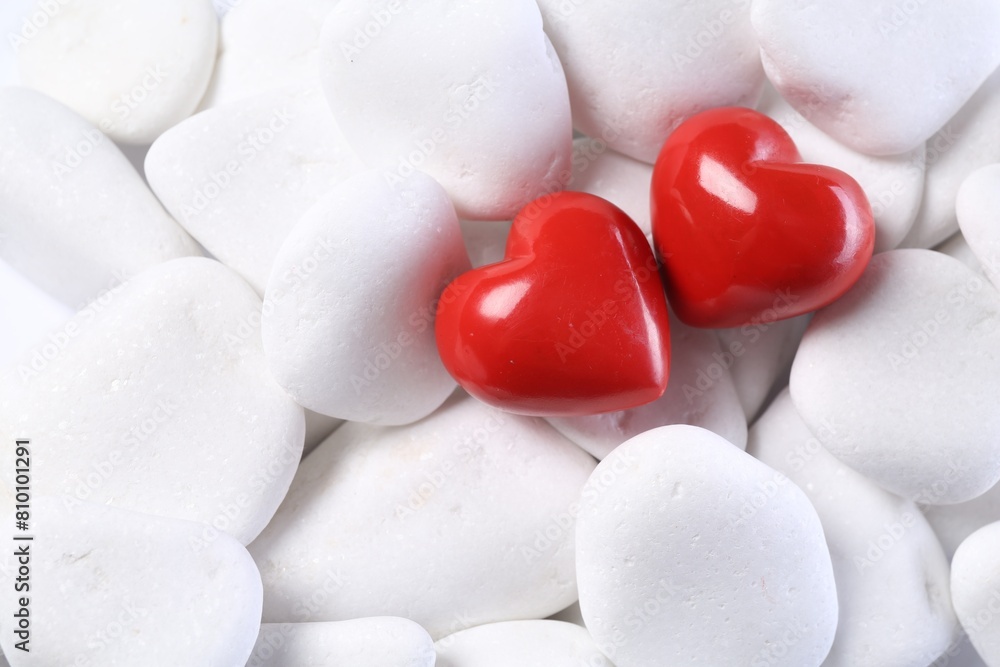 Obraz premium Decorative hearts on white pebble stones, top view