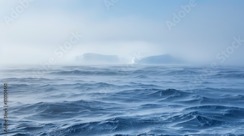  A vast expanse of water, dotted with distant icebergs, on a fog-shrouded day in the heart of the ocean
