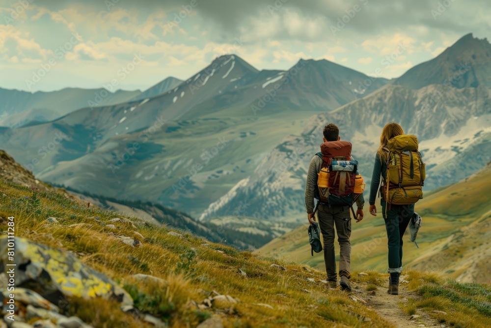 Two people are walking on a mountain trail, them carrying a backpack