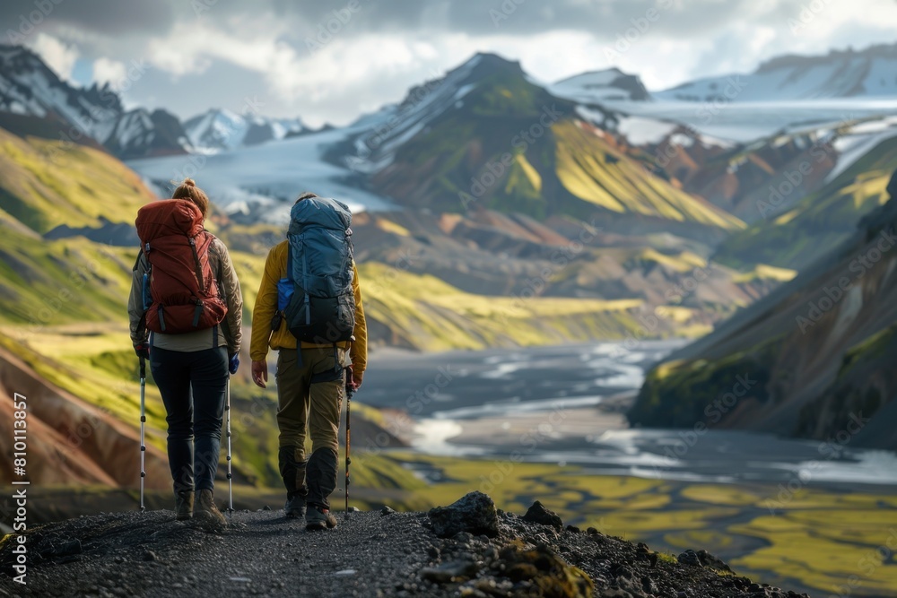 Two people are walking on a mountain trail with backpacks Two people are walking on a mountain trail with backpacks