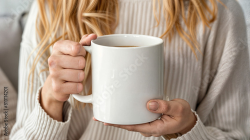 A woman is holding a white coffee mug in her hand