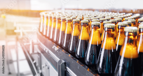 Automated modern beer bottling factory line with glasses bottles on conveyor. Banner Brewery industry food manufacturing  sunlight