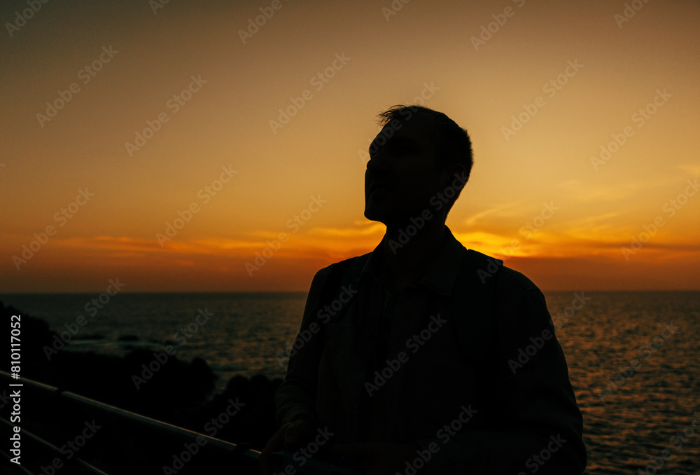 The silhouette of a man contemplating life is outlined against the bright sunset sky on the island of Tenerife, Spain.