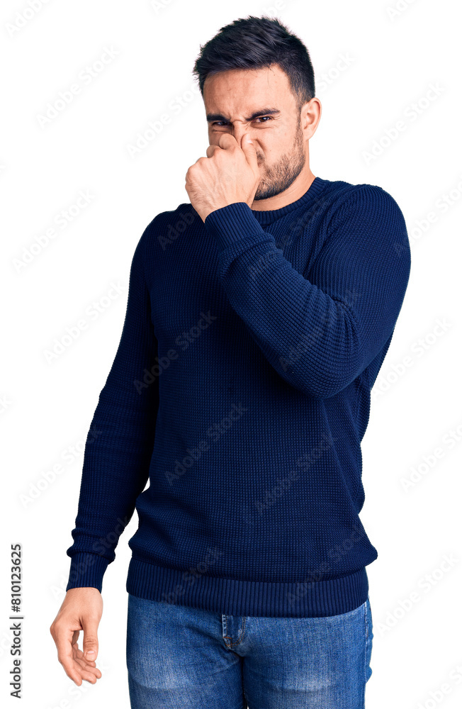Young handsome man wearing casual clothes smelling something stinky and disgusting, intolerable smell, holding breath with fingers on nose. bad smell Young handsome man wearing casual clothes smelling something stinky and disgusting, intolerable smell, holding breath with fingers on nose. bad smell