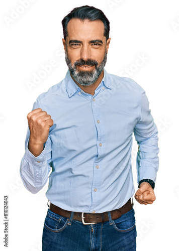 Middle aged man with beard wearing business shirt celebrating surprised and amazed for success with arms raised and eyes closed. winner concept.