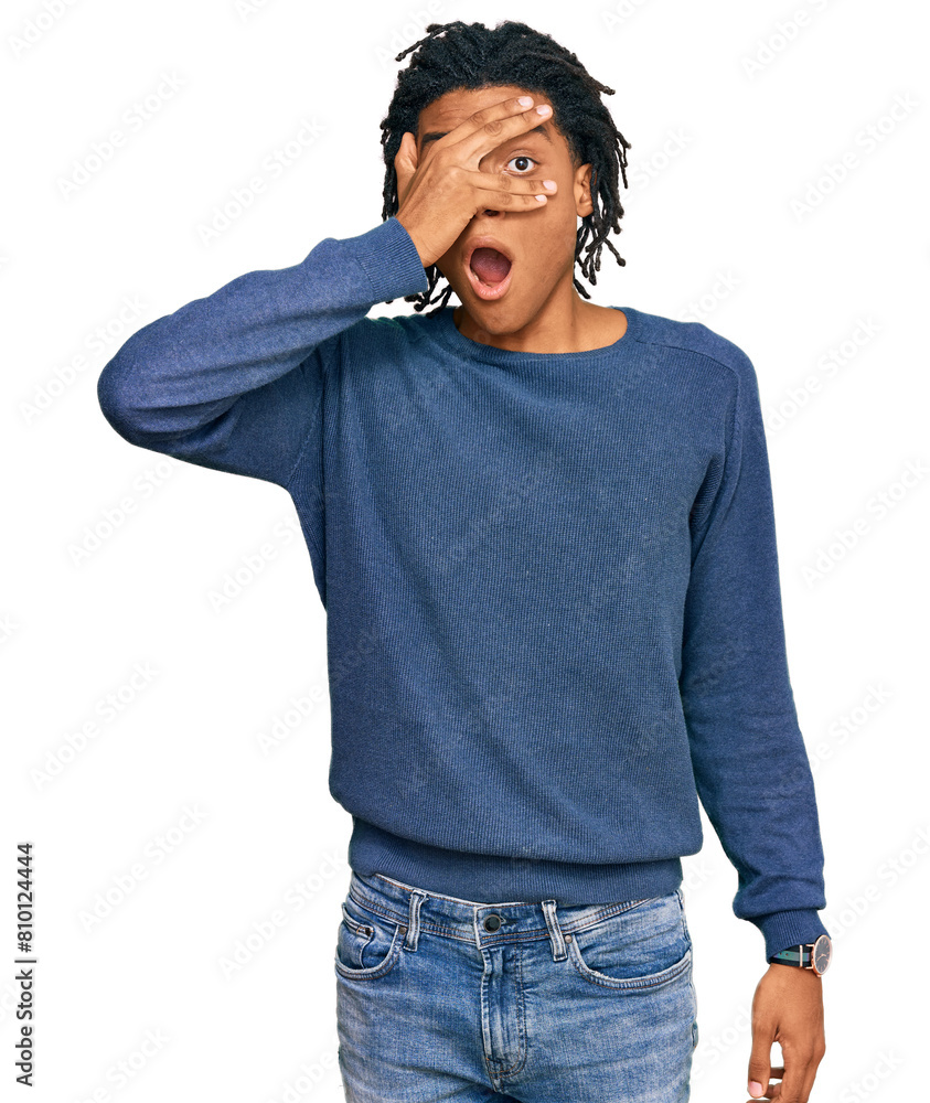 Young african american man wearing casual winter sweater peeking in shock covering face and eyes with hand, looking through fingers with embarrassed expression. Young african american man wearing casual winter sweater peeking in shock covering face and eyes with hand, looking through fingers with embarrassed expression.