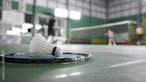 Badminton rackets and white cream badminton shuttlecocks after playing or after games on green floor in indoor badminton court soft focus concept for badminton lovers around the world. photo