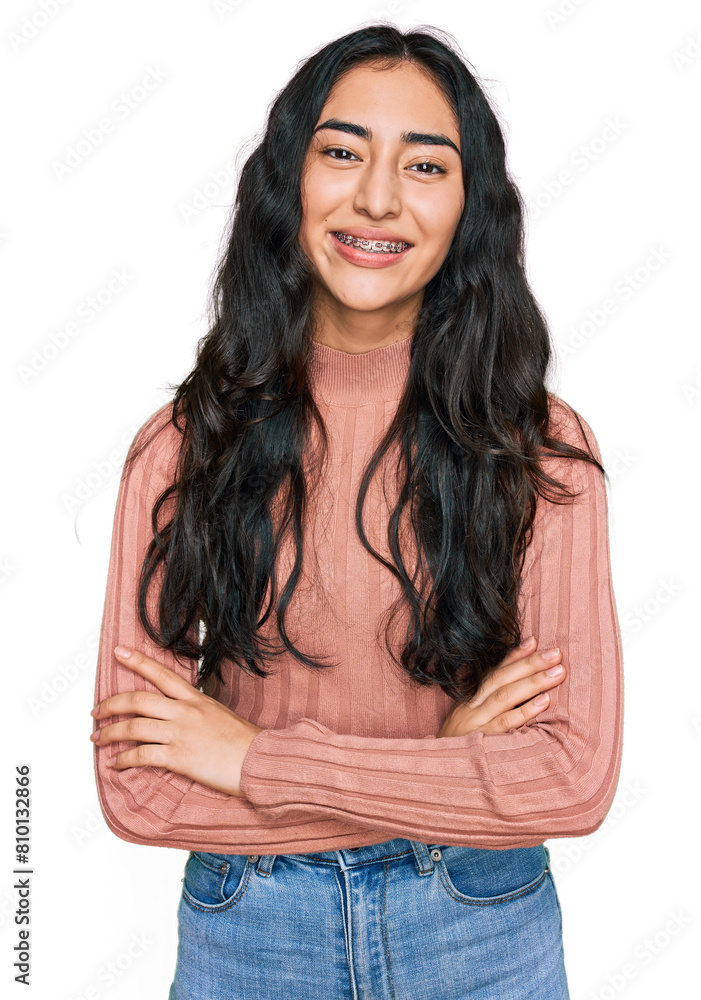 Hispanic teenager girl with dental braces wearing casual clothes happy face smiling with crossed arms looking at the camera. positive person. Hispanic teenager girl with dental braces wearing casual clothes happy face smiling with crossed arms looking at the camera. positive person.
