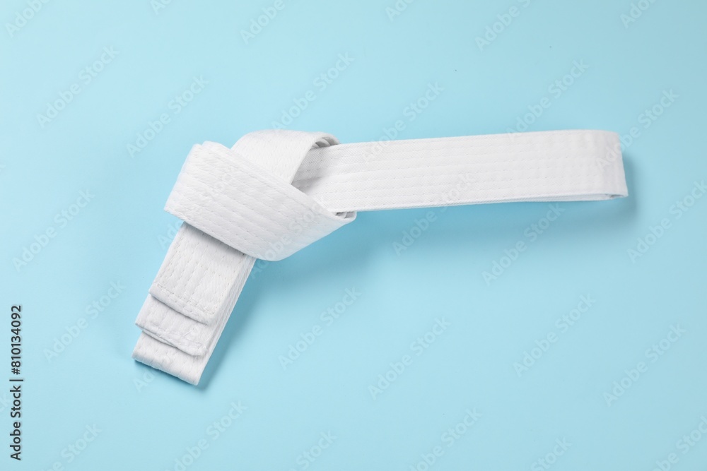 Obraz premium White karate belt on light blue background, top view