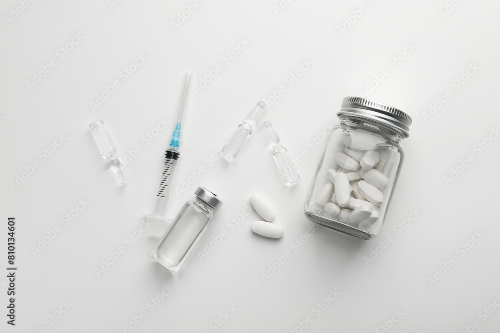 Glass ampoules with liquid, pills and syringe on white background, flat lay Glass ampoules with liquid, pills and syringe on white background, flat lay