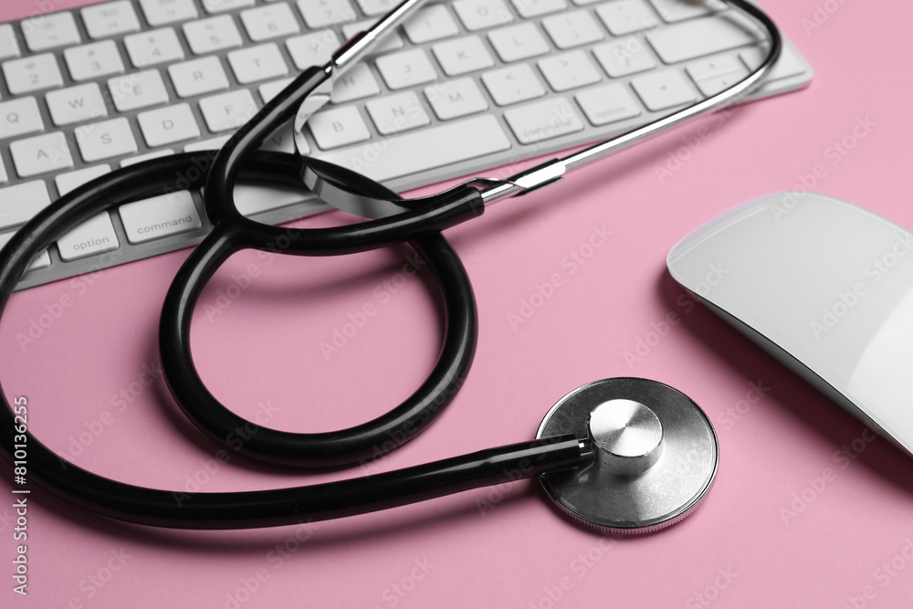 Stethoscope, keyboard and computer mouse on pink background, closeup Stethoscope, keyboard and computer mouse on pink background, closeup