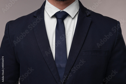 Fototapeta Businessman in suit and necktie on grey background, closeup