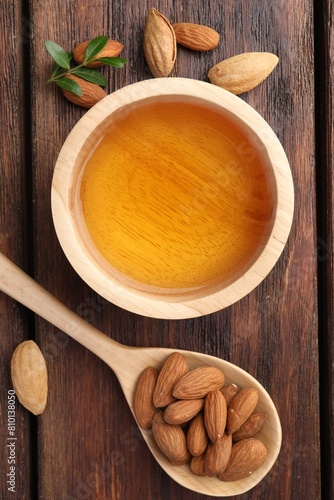Wallpaper Mural Almond oil in bowl, nuts, spoon and leaves on wooden table, flat lay Torontodigital.ca
