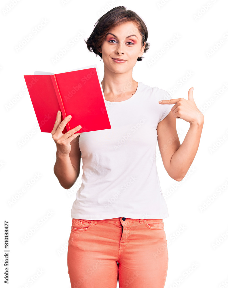 Beautiful young woman with short hair reading a book pointing finger to one self smiling happy and proud Beautiful young woman with short hair reading a book pointing finger to one self smiling happy and proud