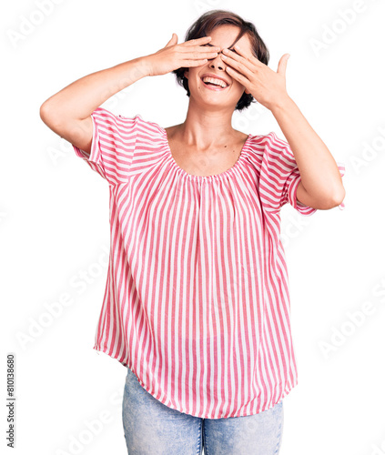 Beautiful young woman with short hair wearing casual summer clothes covering eyes with hands smiling cheerful and funny. blind concept.