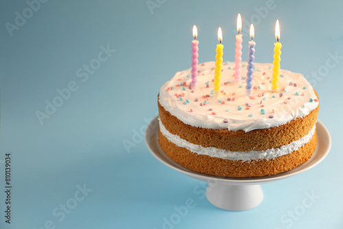 Tasty cake with colorful candles on light blue background, closeup. Space for text