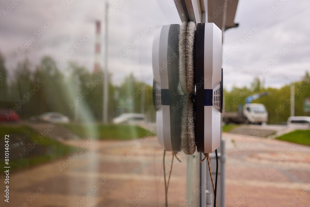 A robotic white Automotive tire is cleaning a glass window A robotic white Automotive tire is cleaning a glass window