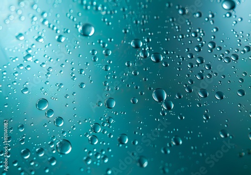 Close-up image of crystal-clear water droplets glistening on a smooth teal surface with varying sizes and reflections