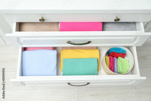 Chest of drawers with different folded clothes indoors, top view photo