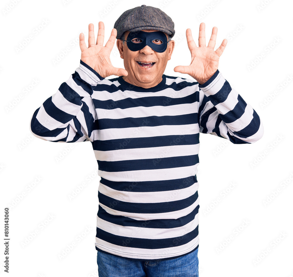 Senior handsome man wearing burglar mask and t-shirt showing and pointing up with fingers number ten while smiling confident and happy. Senior handsome man wearing burglar mask and t-shirt showing and pointing up with fingers number ten while smiling confident and happy.