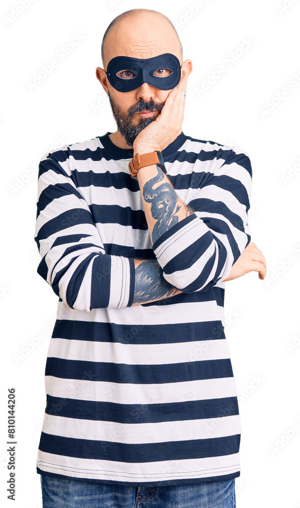 Young handsome man wearing burglar mask thinking looking tired and bored with depression problems with crossed arms. Young handsome man wearing burglar mask thinking looking tired and bored with depression problems with crossed arms.