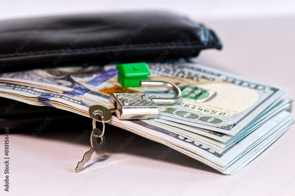 Concept image of money for a new apartment, wallet, stack of hundred dollar bills, keys and a plastic house in the background. Concept image of money for a new apartment, wallet, stack of hundred dollar bills, keys and a plastic house in the background.